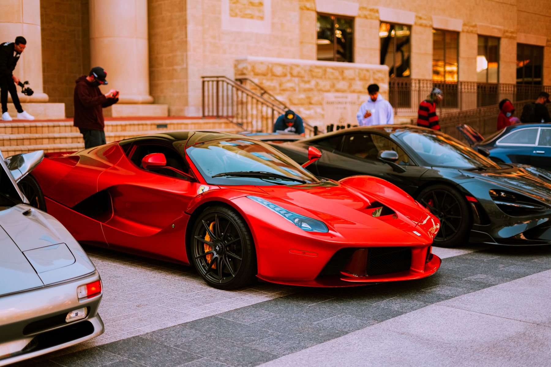 Several exotic sports cars arranged outside an elegant building